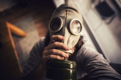 Man wearing vintage gas mask looking up at camera 