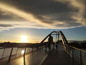 Footbridge over sea against sky during sunset