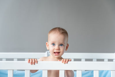 Close-up portrait of cute baby boy sitting on table against wall