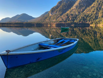 Scenic view of lake sylvensteinstausee and a fishing boat, mountains against sky, bavarian alps 