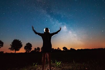 Silhouette of woman standing against sky at night