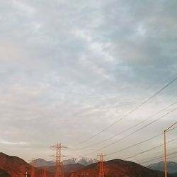 Low angle view of silhouette electricity pylon against sky