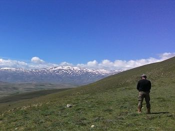 Rear view of man standing on field against sky