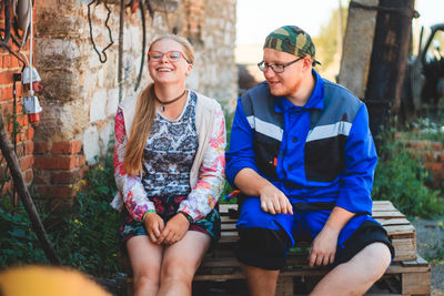 Young friends sitting on wooden crates by brick wall