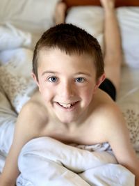 Portrait of boy smiling on bed at home