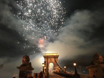 Low angle view of illuminated bridge against cloudy sky