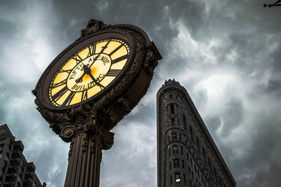 Low angle view of clock tower against cloudy sky in city