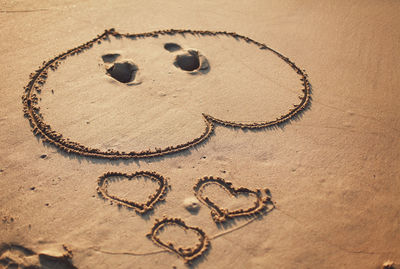 Close-up of heart shape on sand at beach