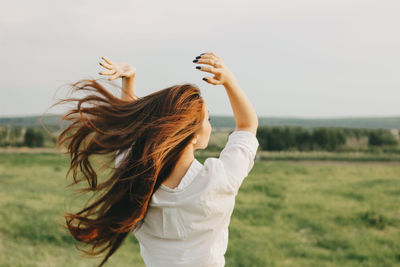 Midsection of woman with arms raised on field