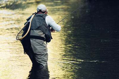 Rear view of man fishing at shore