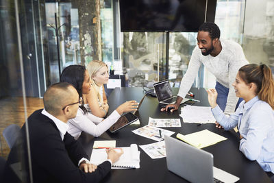 High angle view of smiling multi-ethnic business people discussing in meeting at board room