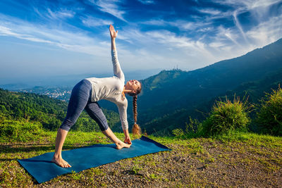 Full length of woman exercising on field