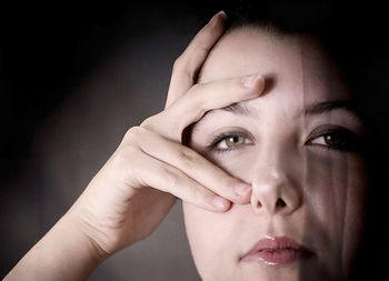 Close-up portrait of young woman over black background