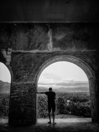 Rear view of man standing at abandoned building 