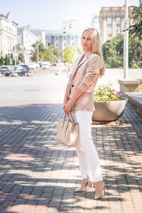 Portrait of a successful business woman with blonde long hair. in an expensive suit,fashionable bag.