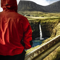 Solo traveller looking towards mulafossur waterfall in the faroe islands