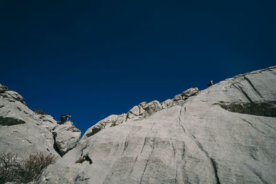 Low angle view of rock formation against clear blue sky
