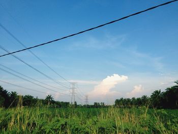 Electricity pylon on field against cloudy sky