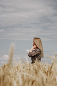 Woman with umbrella in background against sky