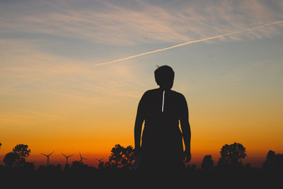 Silhouette man standing against orange sky