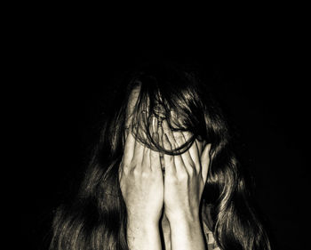 Close-up portrait of a woman against black background