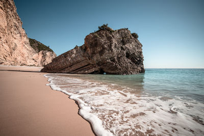 Rock formation on beach against clear sky