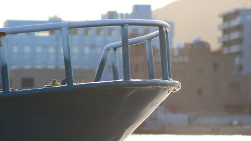 Close-up of metallic railing against sky in city