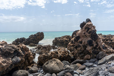 Rocks on sea shore against sky