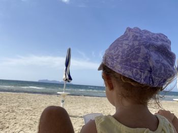 Rear view of woman looking at sea shore against sky