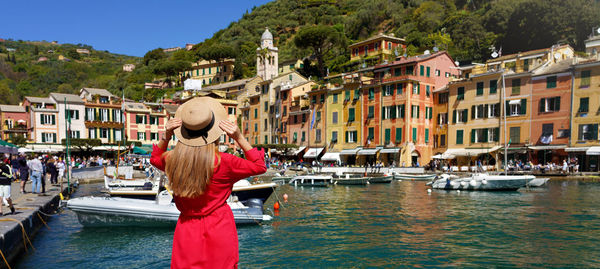 Back view of beautiful girl in red dress enjoying view of the picturesque village of portofino