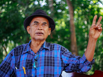 Portrait of young man standing against trees