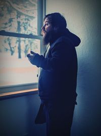 Portrait of young man standing against wall