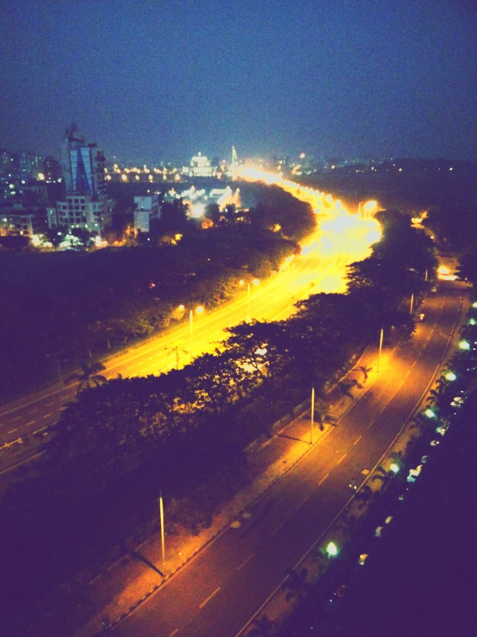 illuminated, city, night, building exterior, cityscape, architecture, built structure, sunset, high angle view, sky, transportation, dusk, sea, city life, water, aerial view, outdoors, orange color, river, no people