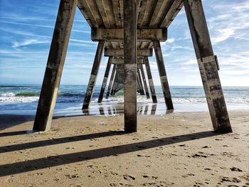 Wooden pier on beach against sky