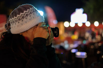 Midsection of woman photographing illuminated city at night