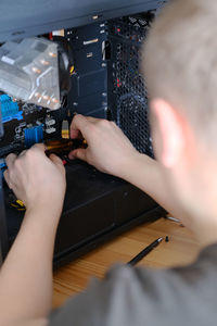 A man disassembles a computer system unit with a screwdriver