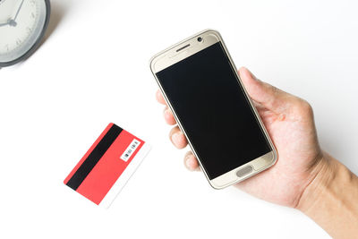 Close-up of hand holding mobile over white background