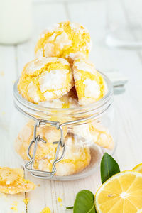 Cracked lemon cookies in small glass jar, on white wooden background , vertical composition