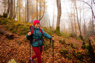 Portrait of smiling young woman in forest during autumn