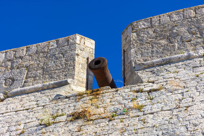 Low angle view of a stone wall against blue sky