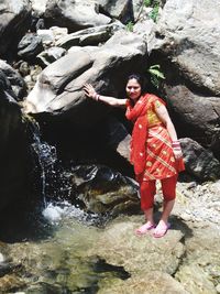 Portrait of woman standing on rock at shore