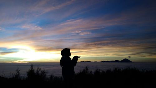 Silhouette man standing against orange sky