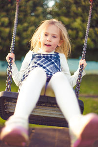 Full length of girl swinging on swing at playground