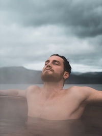 Portrait of young man in water against sky