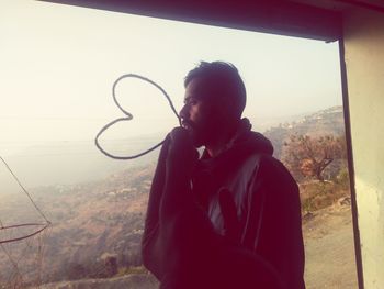 Portrait of young man looking through window