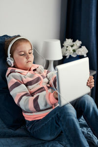 Cute girl wearing headphone using laptop at home