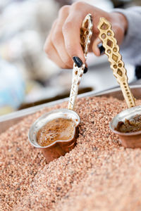 Traditional turkish, arabic coffee brewed in small copper cups in hot sand. close up shot