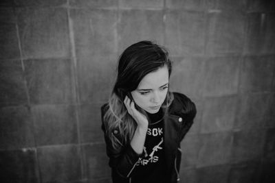 Portrait of a smiling young woman standing against wall