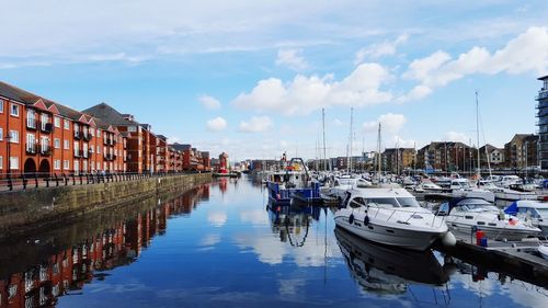 Boats moored in harbor against buildings in city