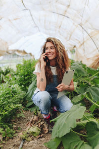 Happy farmer talking on smart phone at greenhouse